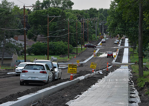 A two-lane road under construction with new curb and sidewalk.