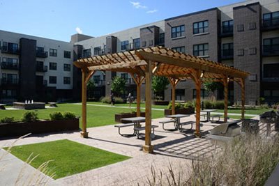 A covered area for picnic tables in the courtyard of a multistory apartment building.