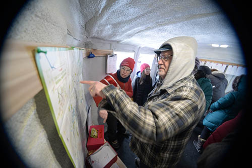 Wide-angle view of people looking at a map inside the art shanty.