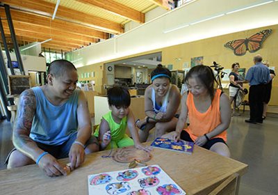 Two adults and two children working on puzzles inside a nature center.