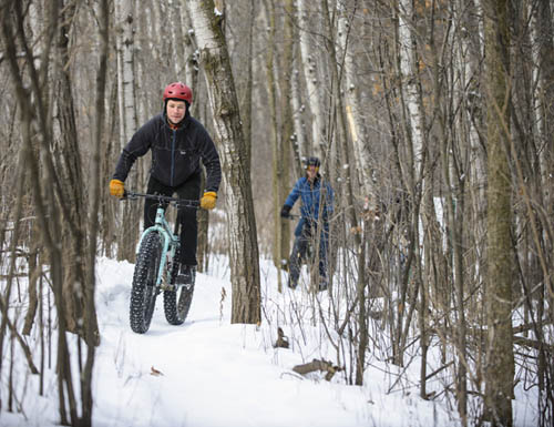 Mountain bikers on snowy trail in the woods