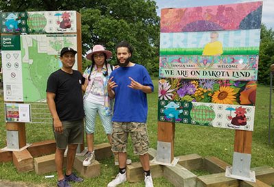 Three of the five artists of color — (from left) Witt Siasoco, Marlena Myles, and CRICE — commissioned to create this signage pose with their work.