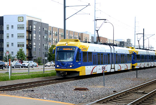 A light rail train passing in front of an apartment building.
