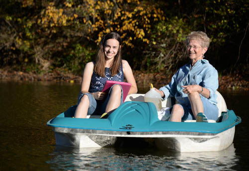 Haley Jostes and Bonnie Juran collect water samples from a small paddleboat.