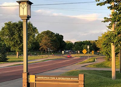 A two-lane road next to a Minneapolis Park & Recreation Board sign.