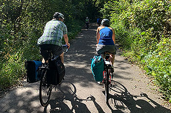 Two people biking on a paved path.