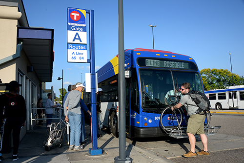 A biker removing their bike from an A Line bus while other people board.