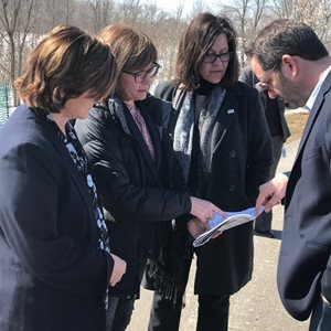 A person pointing at a paper with 3 other people watching.