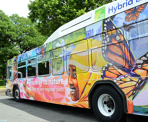 Brightly colored bus shows monarch butterflies and a young woman in a hijab with a butterfly on her hand.