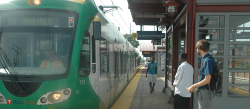 People boarding a Green Line light rail vehicle.