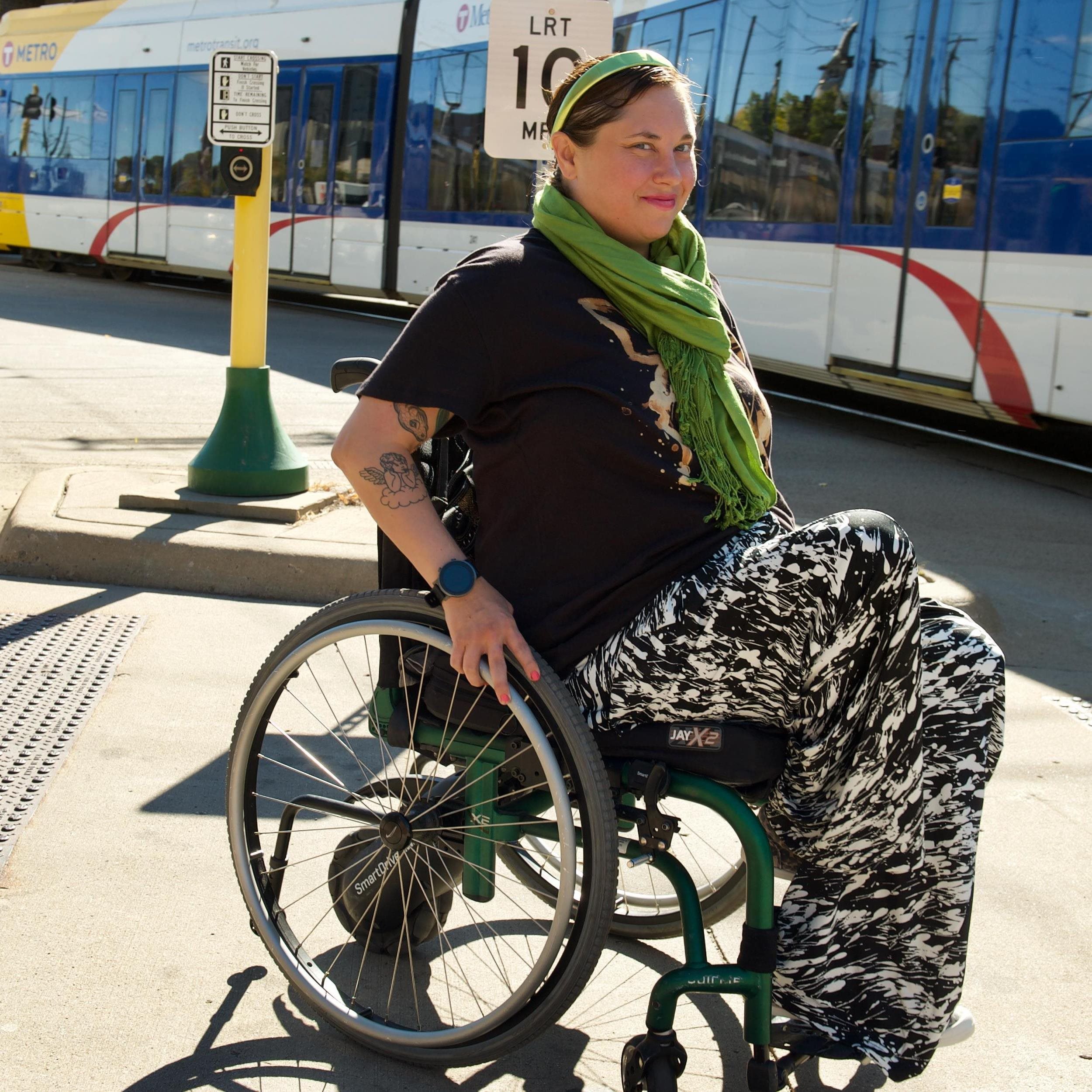 A woman in a wheelchair by a light rail.