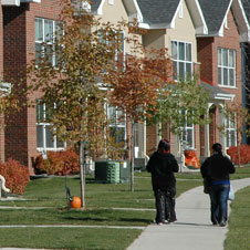 photo of two people walking on the sidewalk outside of a multi-unit townhouse row