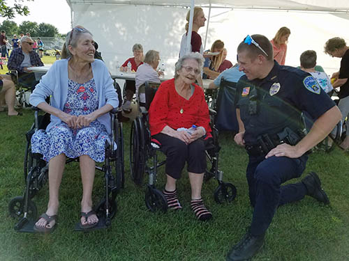 Two people smiling while talking with a police officer.