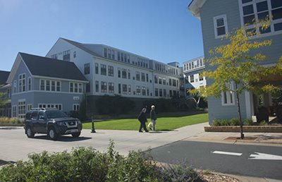 Two people walking between multi-level housing buildings.