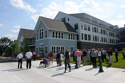 A group of people listening to a speaker in front of a new development.