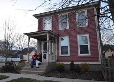 Larry and Caroline Long sit on the steps of their 1868 home in historic downtown Carver.