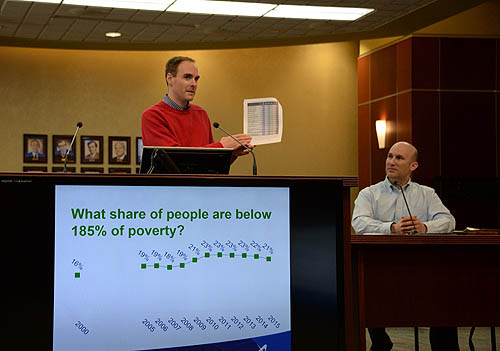 A man speaking at a podium, with another man at a microphone.