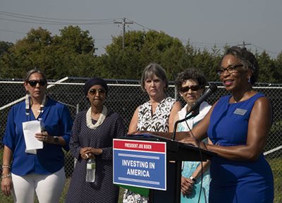 Woman at a podium flanked by four other women.