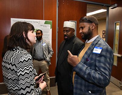 One Met Council staff member and two representatives from Community Resource Center are talking to each other in the lobby near the Met Council chambers.