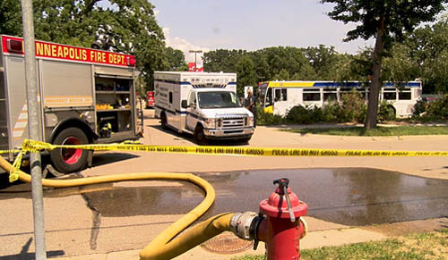 A fire truck and ambulance near yellow police line tape.