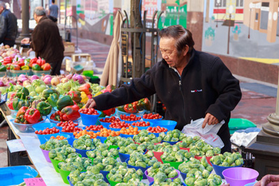 A vendor setting up vegetables for sale at a farmers market.