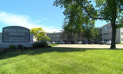 A three-story apartment complex with the Minnetonka Heights Apartments sign in front.