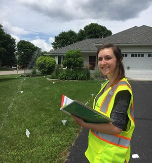 A worker with a clipboard watching a sprinkler system.