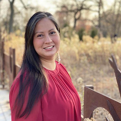 Portrait of Allison Waukau outdoors with trees and tall grasses in the background.