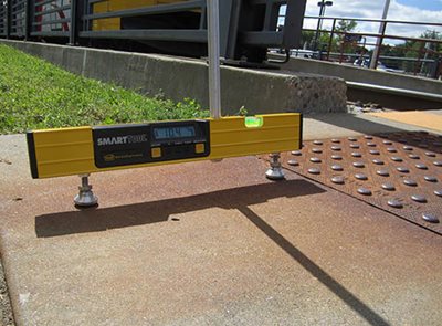 A free-standing level measuring the slope of a sidewalk.