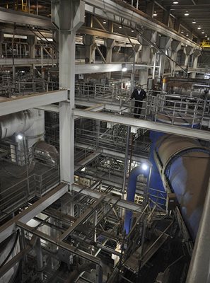 View from third story of building interior shows variety of concrete and metal structures and pipes.