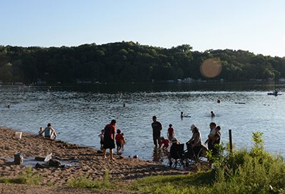 People on a beach and wading in a lake.