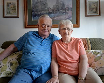 A retired couple sitting on a couch.