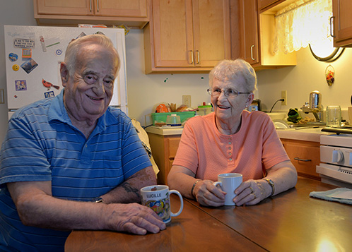 Two people with coffee cups at their kitchen table.
