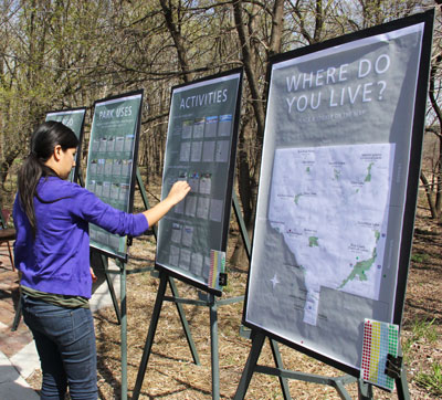 A person places stickers on a board asking for feedback on park activities.