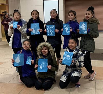 8 youth posing in two rows, each holding a sunprint.