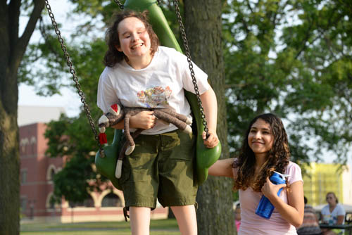 Carly Mauck swings at the new play area as her personal care assistant, Angelica Rodriguez, gives her an occasional push.