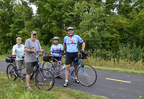 Four adults on tandem bicycles on a trail.