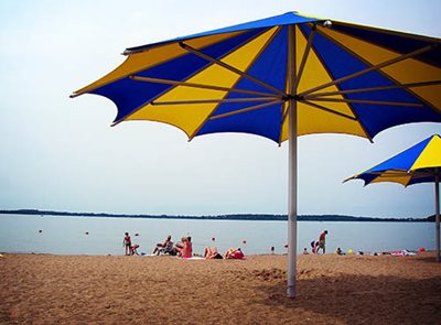 Large purple and gold umbrellas and families close to the water on the beach.