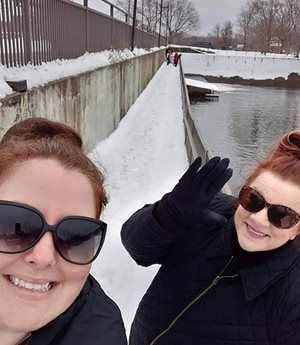 Selfie of two people posing next to open water.