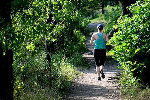 A person jogging on a gravel path.