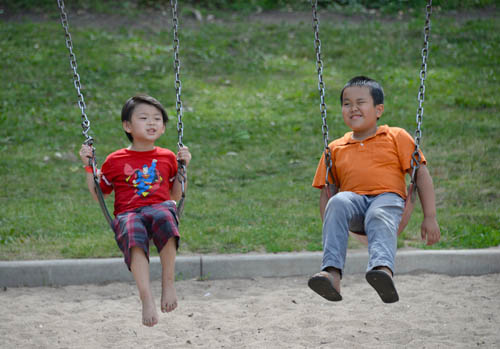 Boys enjoy swinging in a play area at Phalen-Keller Regional Park during Dragon Festival 2016 on July 10.