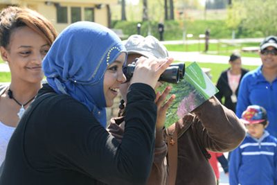 A person looking through binoculars at a park.