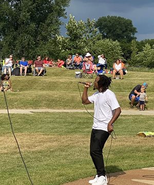 A person singing into a microphone at a parks event.