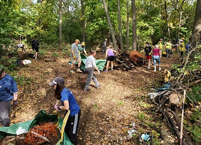 People on wooded trails bagging debris and collecting old boards.