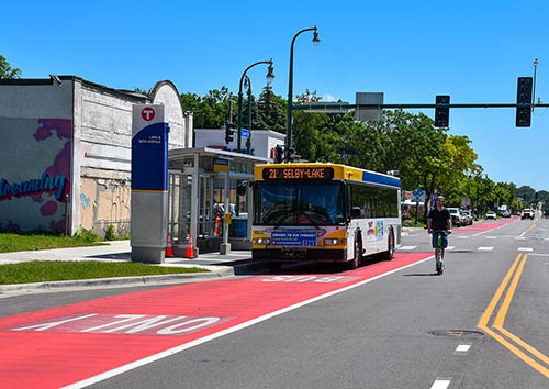 Route 21 bus stops in red-painted bus-only lane at a future METRO B Line station on East Lake Street.