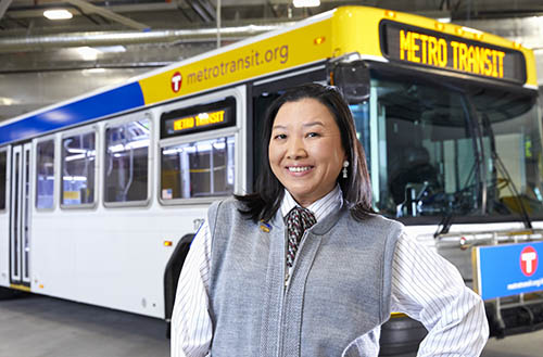 Bus operator stands in front of a Metro Transit bus.