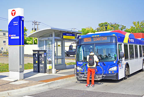 Man loads bike to rack on METRO C Line bus.