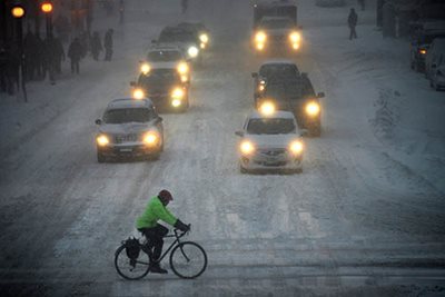 A bicyclist navigates a snowy intersection.