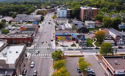 Commercial buildings, a wide street, and trees.