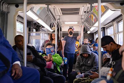 A man in a mask stands on crowded Metro Transit bus.